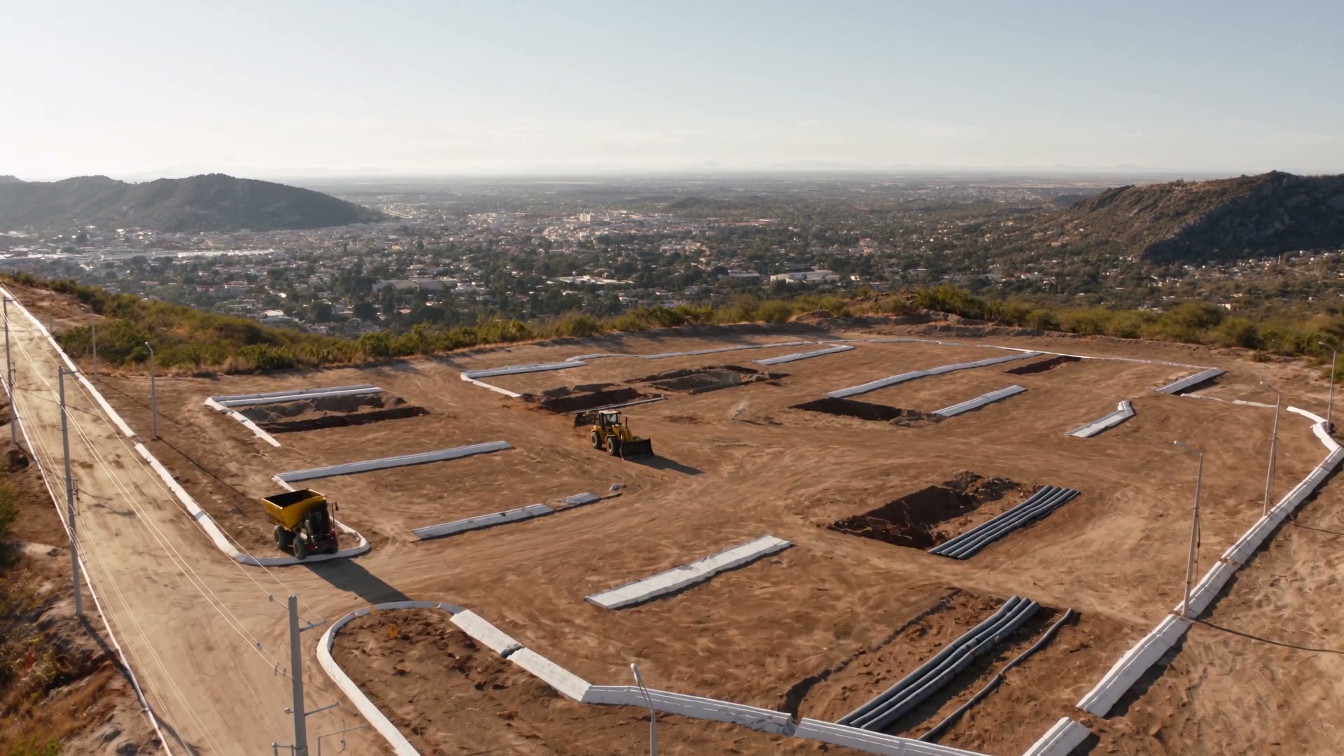 Vista aérea de obra de urbanización: vialidades trazadas, guarniciones y tubería de drenaje